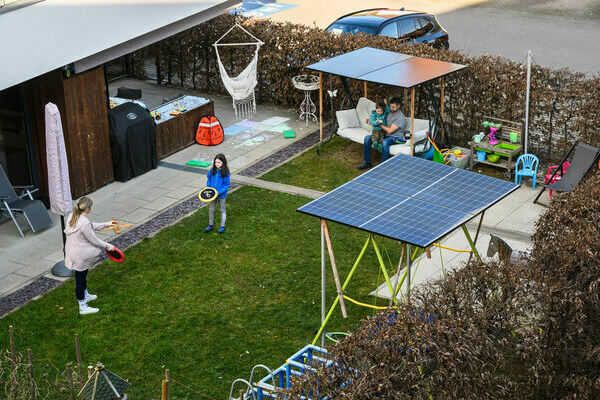 Eine Familie spielt im Garten bei einer selbstgemachten Beschattung die gleichzeitig Energie Produziert. 