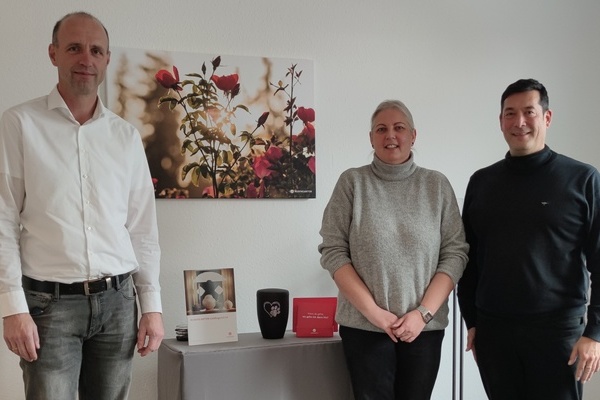 Herr Thorsten Hermes (Abteilungsleiter Filialmanagement), Frau Sandra Gall (Gebietsleiterin Baden-Wrttemberg), Brgermeister Markus Hollemann stehend vor einem Rosen-Bild und einer Urne in der Mitte