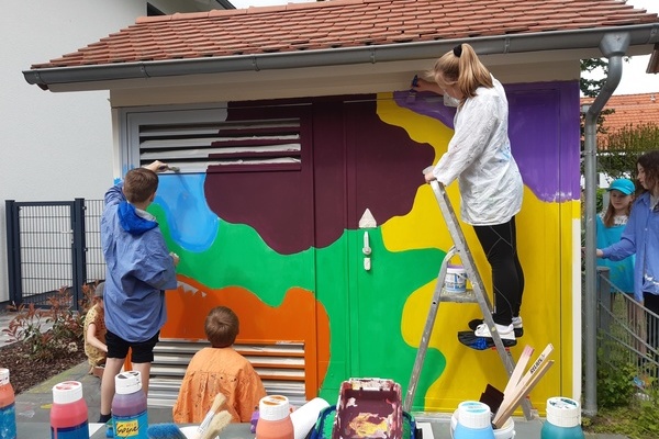 Drei Kinder, die ein Stromh&auml;uschen bemalen