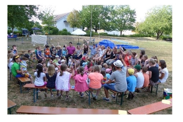 Viele Kinder sitzen drau&szlig;en im Kreis mit B&uuml;rgermeister Hollemann und Betreuer der Jugendpflege