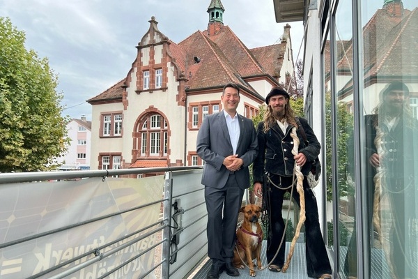 Wandergeselle Tom Adler mit seinem Hund Lotus (rechts) und Bürgermeister Markus Hollemann auf dem Balkon am Rathausplatz. Foto: Gemeinde Denzlingen