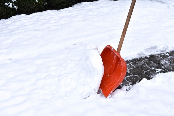 Beim Schneerumen mit roter Schneeschaufel